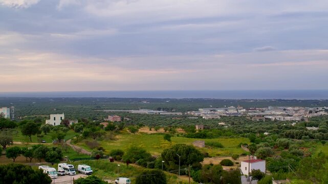 Monopoli, Bari Metropolitan City, Puglia, Italy, featuring olive groves, agricultural fields, scattered farmhouses and the Adriatic coastal plain beneath soft evening skies, elevated panning panoramic