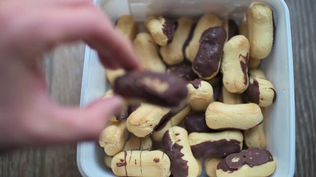 Mini eclairs small size bites in product packaging hand holding macro puff Bavarian cream pastry macro with texture closeup