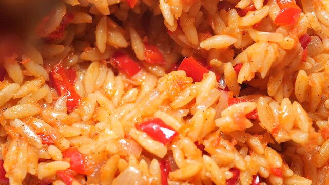Cooking orzo with red peppers and spices in the kitchen