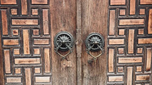 Ancient Ottoman wooden door decorated with traditional handmade Kundekari carving art in Istanbul, Turkey. Authentic historic gate with vintage metal knockers, rich oriental culture concept.