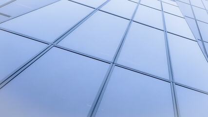 Fototapeta premium Modern corporate skyscraper glass facade with geometric window panels and clean linear architecture pattern