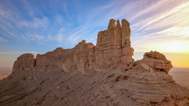 Beautiful sandstone mountain ridge and desert cliffs in Saudi Arabia under scenic sunset sky with clouds