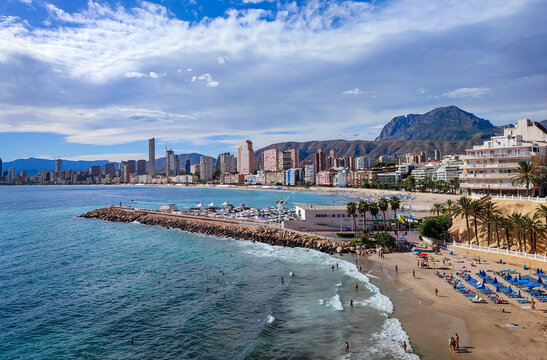 Panoramic view of Benidorm city skyline with sandy beach resort buildings and high mountains near sea