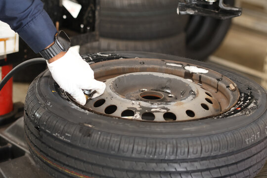 Close-up of the process on a tire-changing machine: a mechanic dismounts a car wheel (removing a tire from or mounting one onto a stamped steel rim).