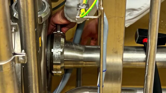 Worker tightens and inspects stainless steel pipe fitting in industrial facility