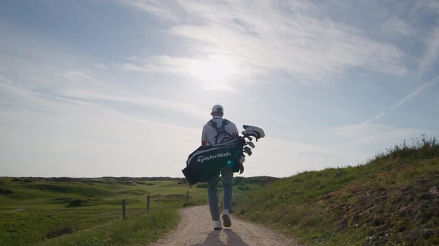 Following golfer entering golf course on foot at sunrise