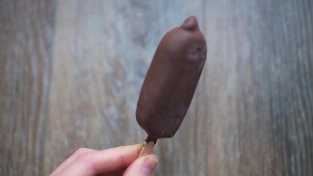 Ice cream double milk chocolate coating, caramel sauce filling stick bar hand holding sweet dessert food treat in summer