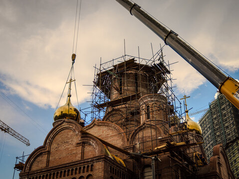 A crane lifts the dome with a cross for erection on the church.