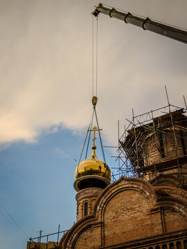 A crane lifts the dome with a cross for erection on the church.