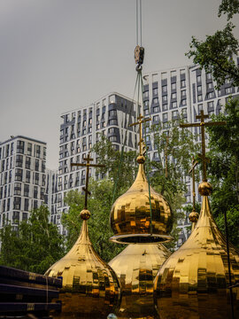 A crane lifts the dome with a cross for erection on the church.