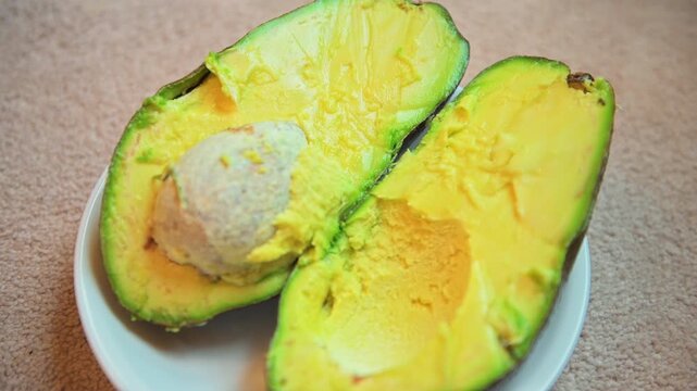 Florida avocado green fruit cut in half food on white plate with pit macro closeup healthy fats for health plant based low carb diet