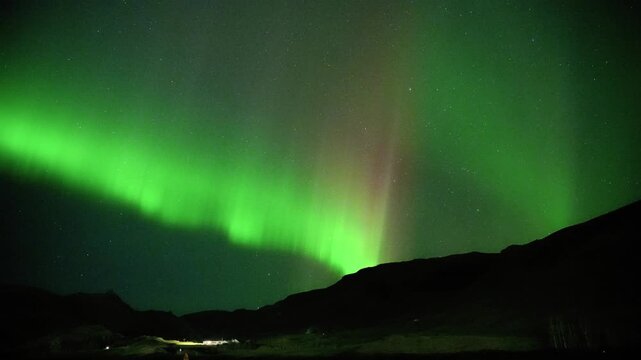Green Northern Lights With Red Hues Illuminating Silhouetted Mountain Ridges At Night In Hveragerdi, Iceland. real-time, static shot