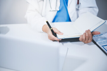 Fototapeta premium Middle aged female doctor working on laptop in doctor's room