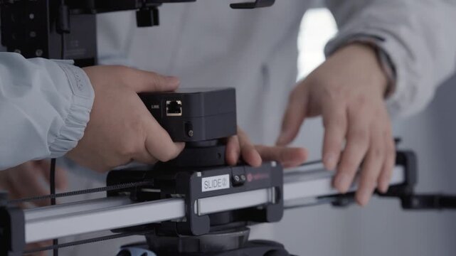 Close up of Videographer Hands Setting Up Camera Slider Equipment for Video Production