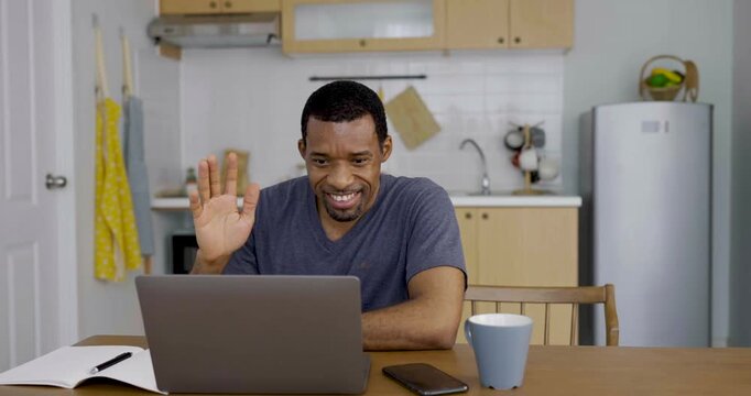 Happy African american business afro man waving at laptop during online video meeting at home, showing remote Freelance communication, teamwork,  virtual connection.