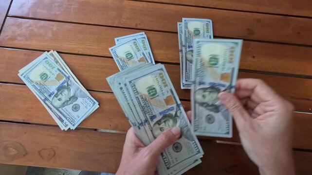 Woman hands counting stack of 100 dollar bills put in stack on table, leafing through banknotes. Close-up. Concept of distribute money for different purposes. Financial planning, savings. 