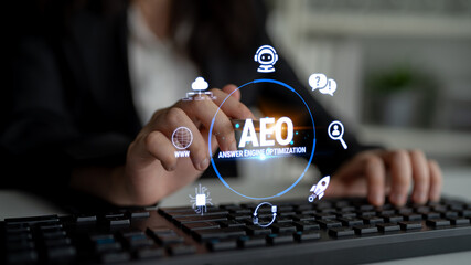 Obraz premium Hand Operating Keyboard with AEO Graphic Overlay for Answer Engine Optimization in Modern Business Environment Fluxor.