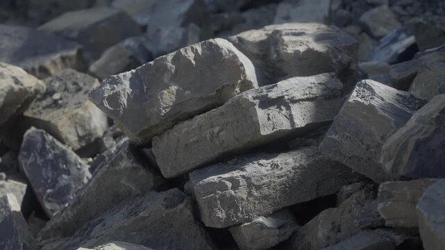 Close-up of large quarried stone blocks stacked in a rock pile. Rough-cut boulders and fractured material showcase extracted aggregate and raw construction resources from a quarry site.