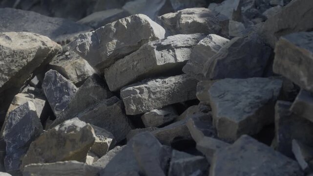 Close-up of large quarried stone blocks stacked in a rock pile. Rough-cut boulders and fractured material showcase extracted aggregate and raw construction resources from a quarry site.