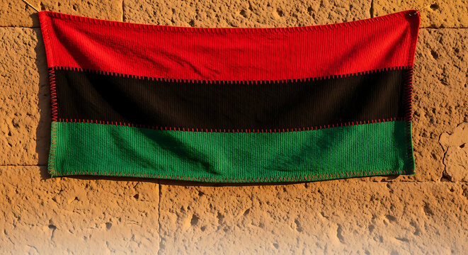 Pan African flag hanging on a textured stone wall symbolizing Black liberation culture and heritage