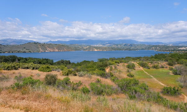 Scenic Lake Cachuma panorama with rolling hills, blue sky, and dry California grassland in natural daylight.