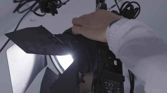 Close up of Lighting Technician Hands Adjusting Professional Studio Light for Video Production