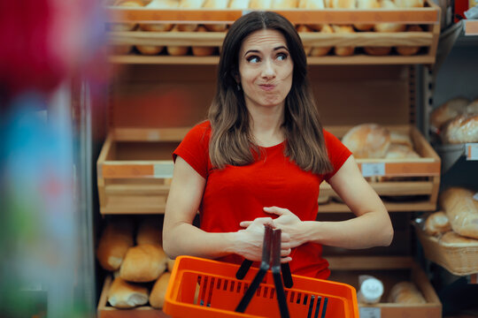 Gluten Intolerant Woman in front of Bakery Shelf Touching her Belly. Female shopper experiencing stomach pain near bread aisle due to wheat allergy symptoms