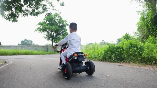 cute boy celebrating independence day on toy bike carrying indian national flag