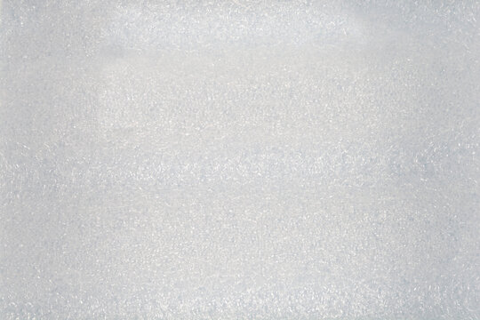 A full frame top view background showing the textured porous surface of a white polyethylene foam protective packaging sheet