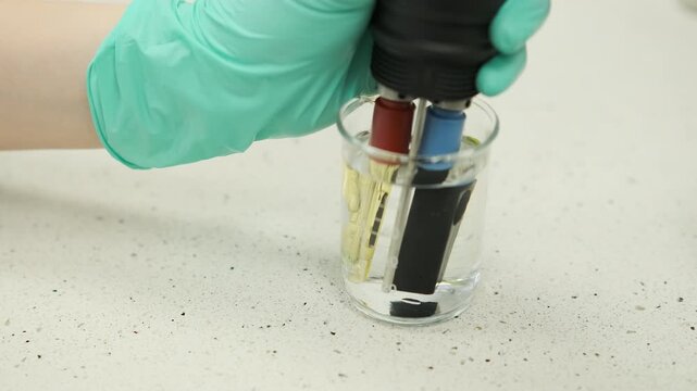 Close up footage of laboratory water analysis using a multiparameter device measuring pH and conductivity. Environmental chemistry testing, water quality assessment, scientific research process.