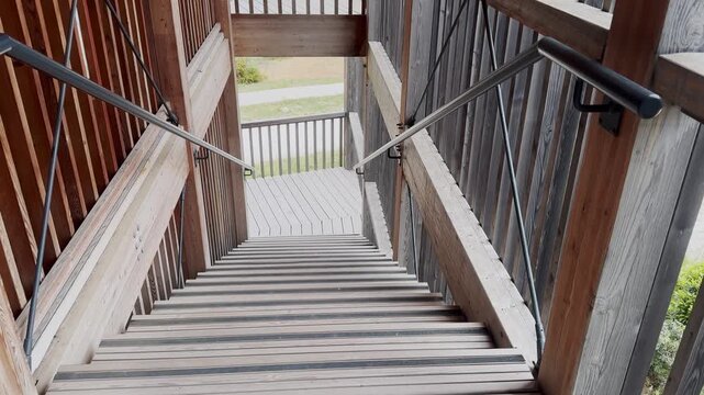 Wooden outdoor staircase with metal handrails and deck boards, showing rustic architecture, access design and cabin-style construction detail.
