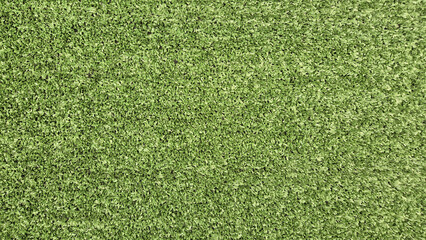 A top-down, full-frame shot showcases a dense, uniform texture of bright green artificial turf or synthetic grass blades. © aura