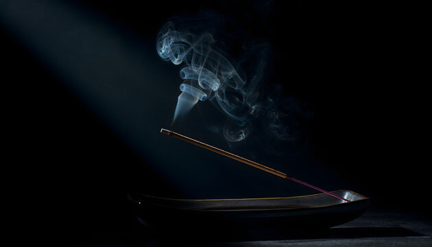 Sandalwood incense stick burning on a dark ceramic burner under a light beam creating a mysterious calming spiritual atmosphere generative AI