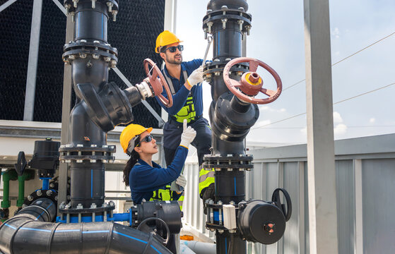 Workers maintaining industrial pipes, Professional engineers inspecting industrial cooling system pipes and valves, Technicians working on plumbing repairing in large HVAC system