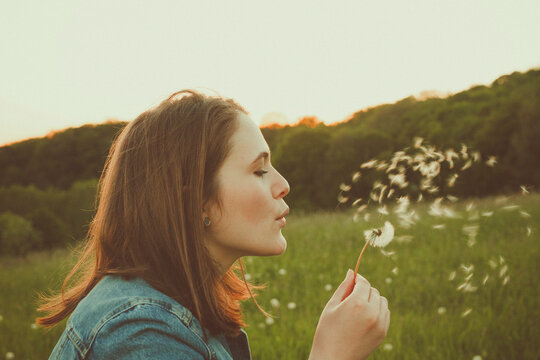 Profile of teenage girl blowing blowball