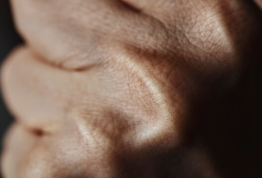 Extreme closeup of a clenched human fist showing skin texture