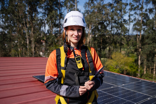 Technician standing on rooftop with solar panel and safety gear