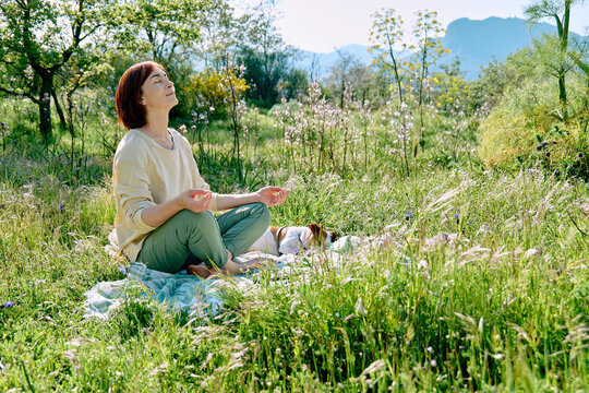 Dog owner meditating in spring meadow with loyal pet