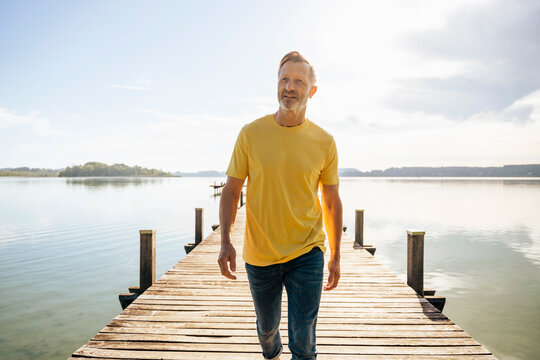 Mature man walking on pier at lake