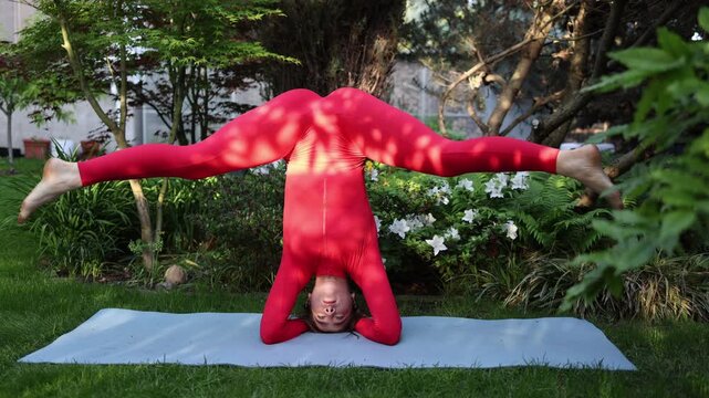 Vertical screen Young woman practices advanced headstand split outdoors demonstrating flexibility body control and dedication developed through years of yoga training
