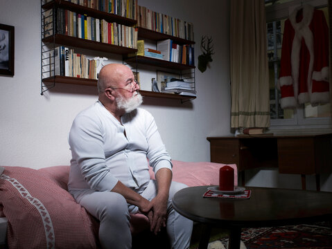 Thoughtful Santa Claus sitting indoors preparing for Christmas