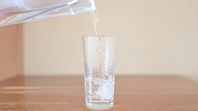 Glass of water poured from a water jug.