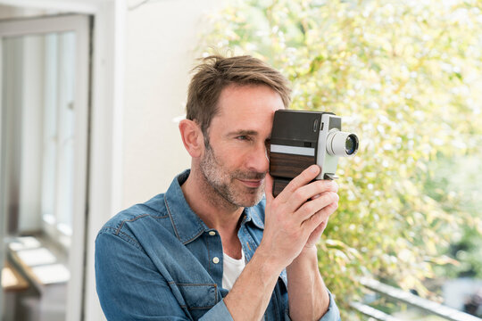 Portrait of mature man with movie camera on balcony