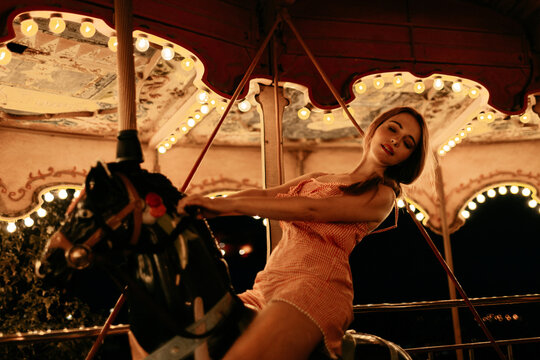 Rider enjoying a carousel horse at an amusement park at night
