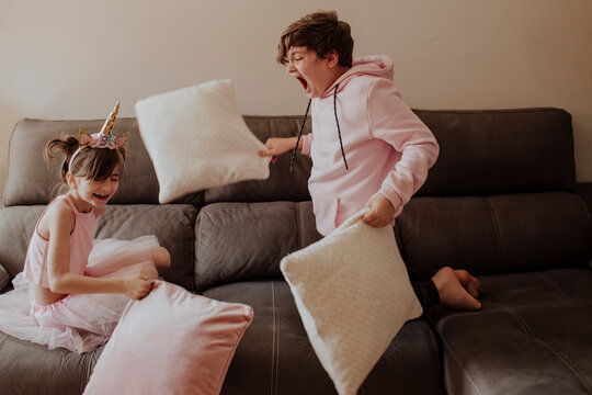 Children having a fun pillow fight on the sofa at home