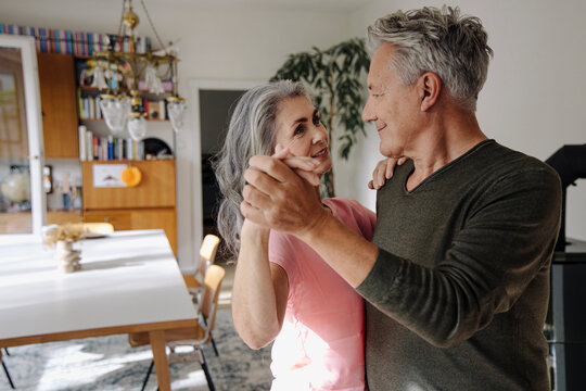 Senior couple dancing in living room at home