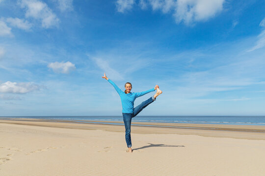 Woman balancing and stretching on a sunny beach by the sea