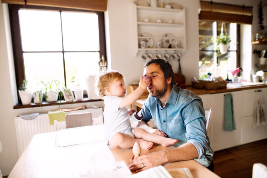 Father having fun with little boy sitting on kitchen table