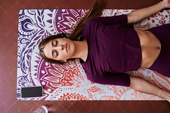 Young brunette woman practising yoga in student dorm