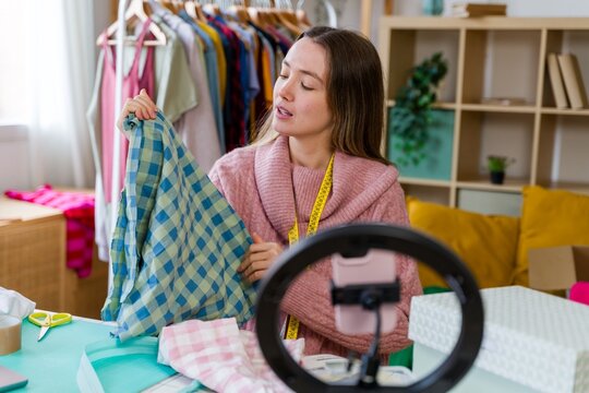 Fashion vlogger recording video presenting checkered shirt indoors